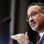 U.S. Secretary of Education Miguel Cardona gestures while speaking into a microphone
