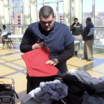 A student with short dark hair folds laundry as part of a relay race of life skills