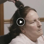 A home health aide brushes an older woman's hair