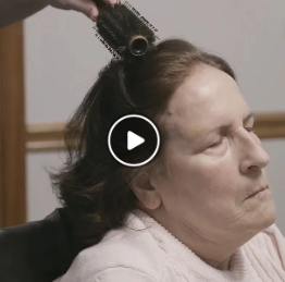 A home health aide brushes an older woman's hair