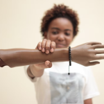 A person with dark-toned skin holds a dark-toned prosthetic arm