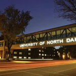 A pedestrian bridge with the University of North Dakota lighted sign across it.