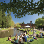 Students at Willamette University sit outside along a waterway