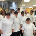 A group of Kitchen School students in chef's jackets