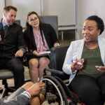 A group of people in work clothing. One is in a wheelchair.