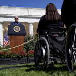 President Biden speaking from the White House lawn to an audience including people in wheelchairs.