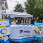 A table with Habitat for Humanity tablecloth and posters.