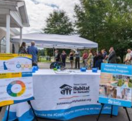 A table with Habitat for Humanity tablecloth and posters.