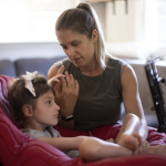 Jenny Eckart Hoyt directs her daughter Winnie's attention to an "eye gaze" device in their home