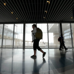 A few people walk through an airport